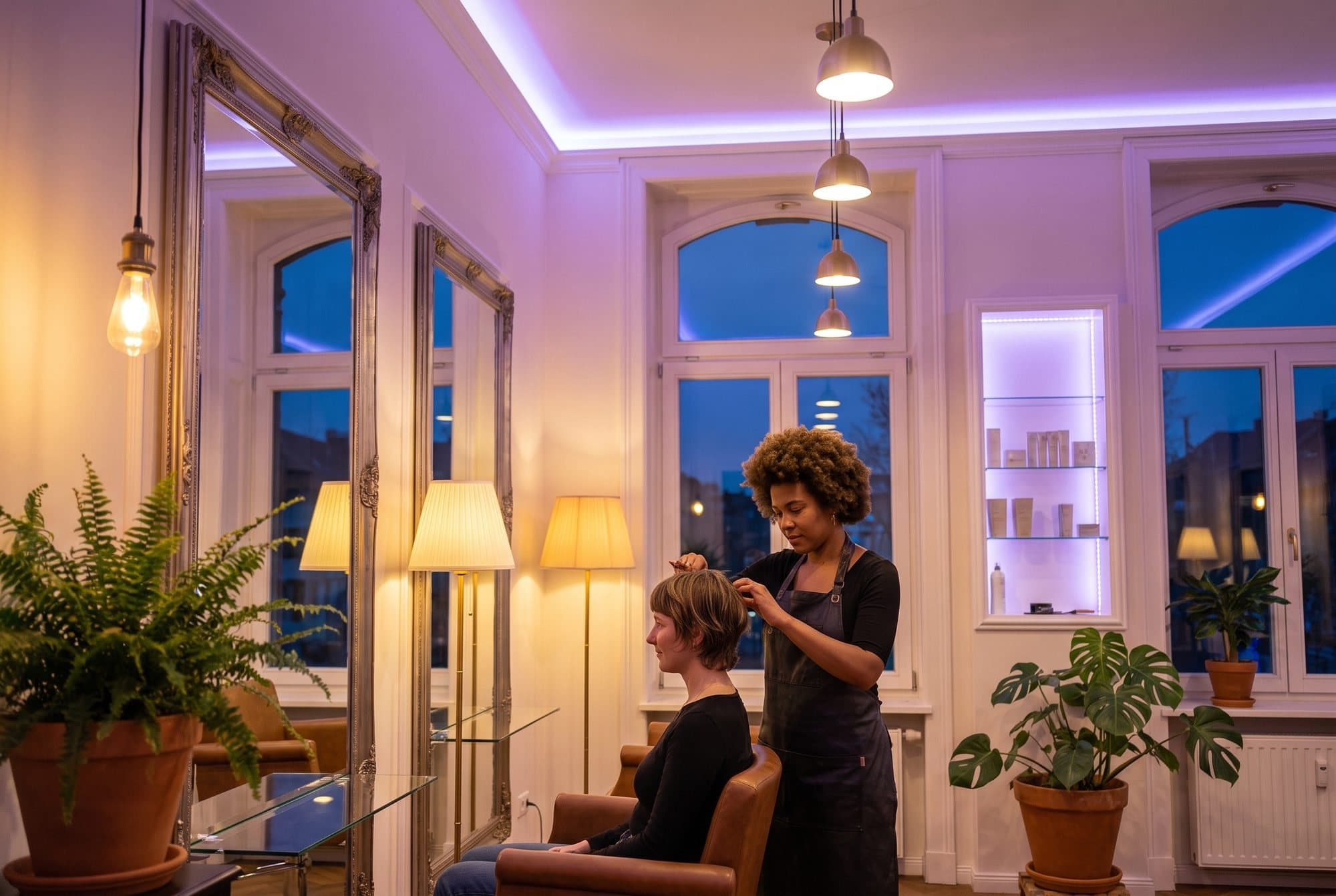 Kapster aan het werk in een salon met hoge boogramen